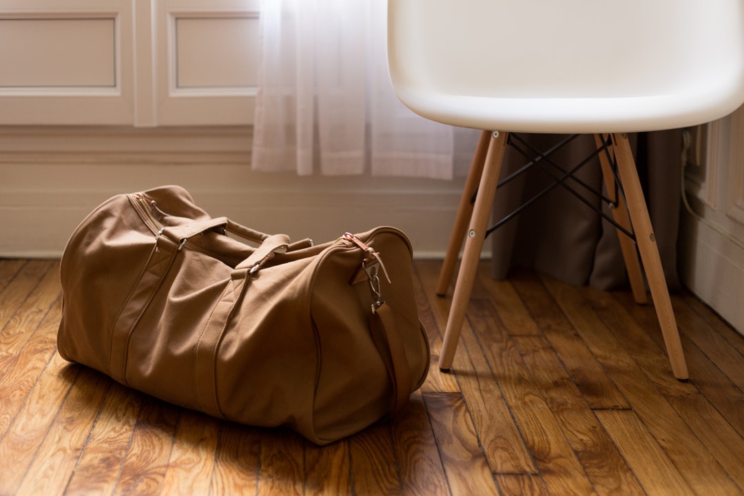 Brown canvas duffle bag sitting on floor