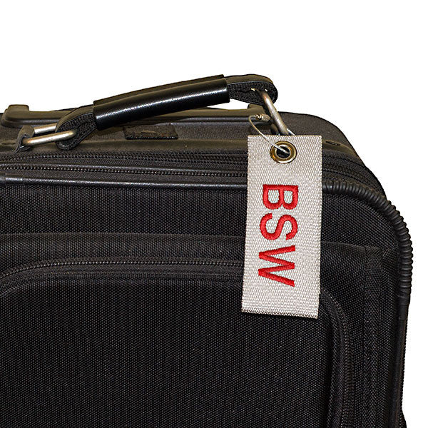 gray extreme bag tag with red text shown on luggage