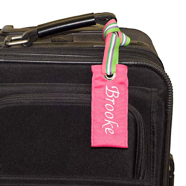 Personalized pink luggage tag shown on black suitcase