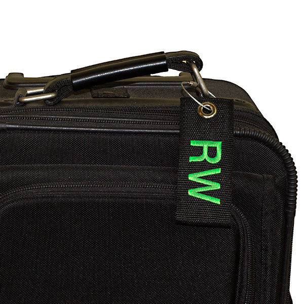black extreme bag tag with green text shown on suitcase