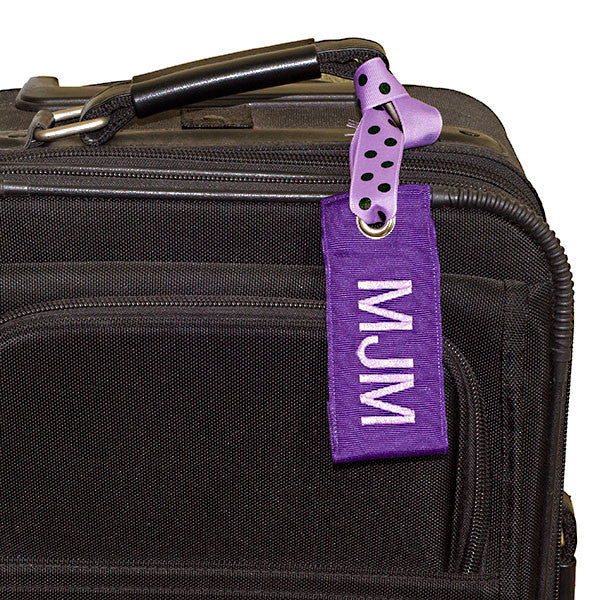 Dark purple luggage tag shown on suitcase