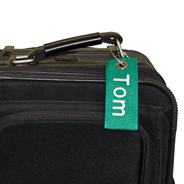 green extreme bag tag with white text shown on suitcase
