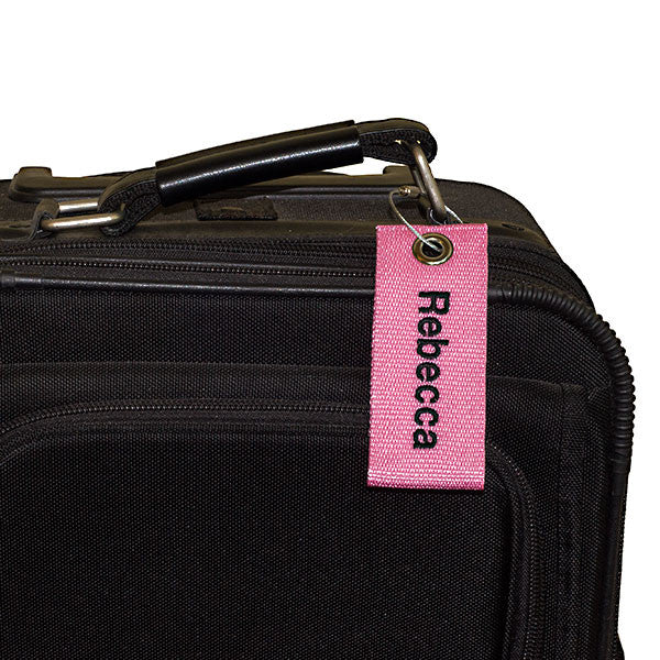 pink extreme bag tag with black text shown on luggage